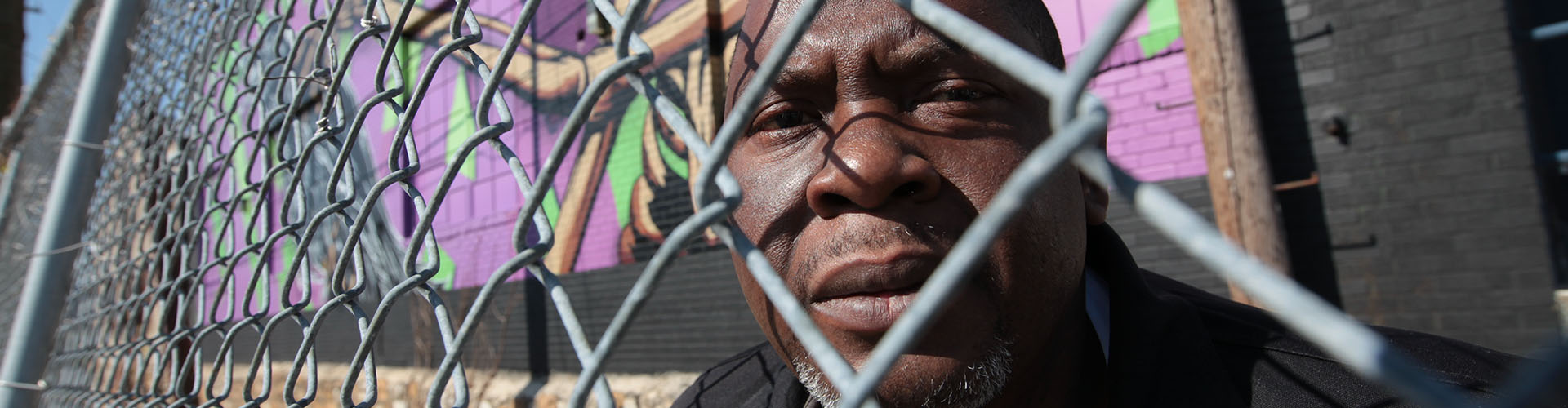 Close up of serious man's face behind chain link fence